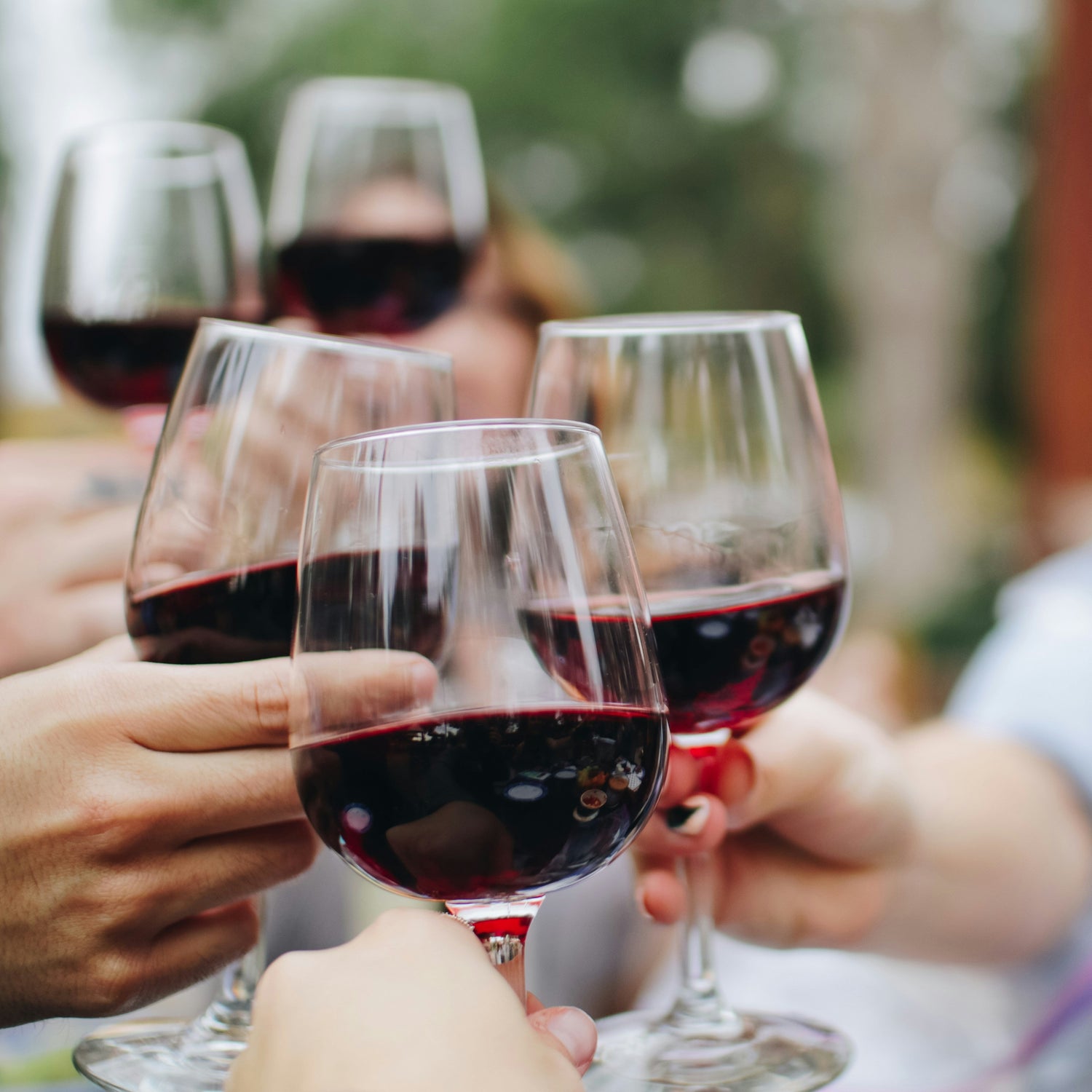 People holding glasses of red wine outdoors